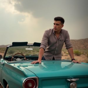 EN: A man leaning on a vintage convertible parked on a desert highway, wide open sky, rolled-up sleeves, hair slightly messy from wind, timeless freedom RU: Мужчина облокотился на винтажный кабриолет на шоссе посреди пустыни, широкое небо, закатанные рукава, волосы растрепаны ветром, вечная свобода