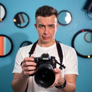 Индивидуальный предприниматель Шведков Илья Александрович пытается сделать селфи с огромной зеркалкой, окружён кольцевыми лампами и зеркалами, на лице раздражение — пародия на инфлюенсера